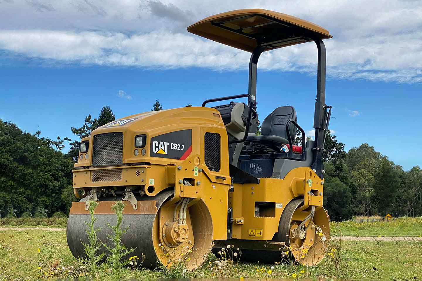 Roller sitting on grass with a blue sky and cloudy background