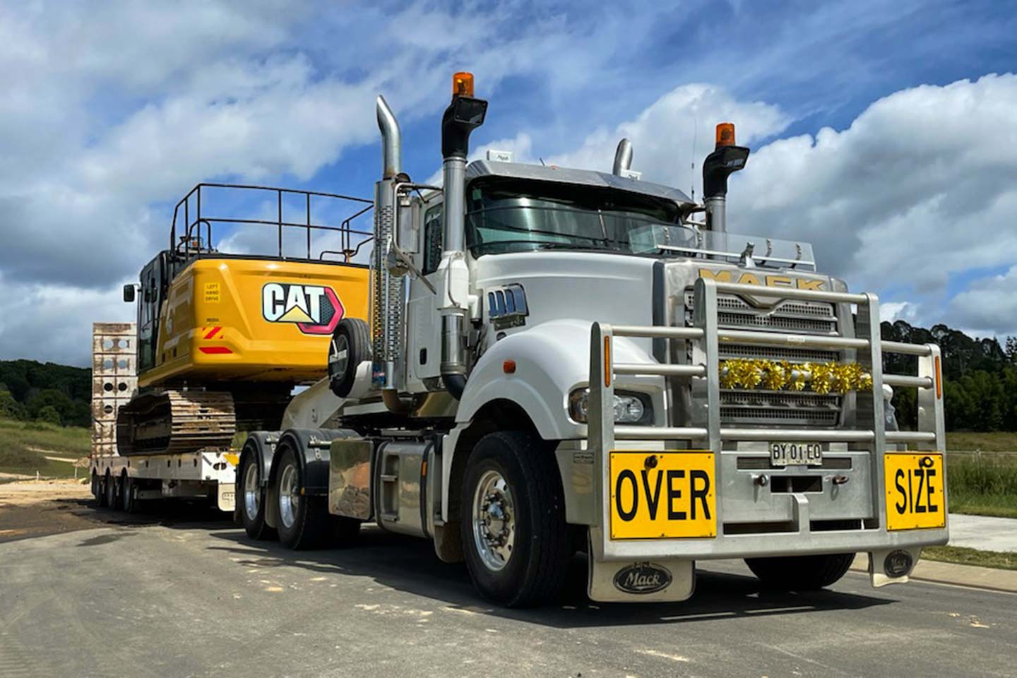 A float truck with a CAT excavator on its back tray