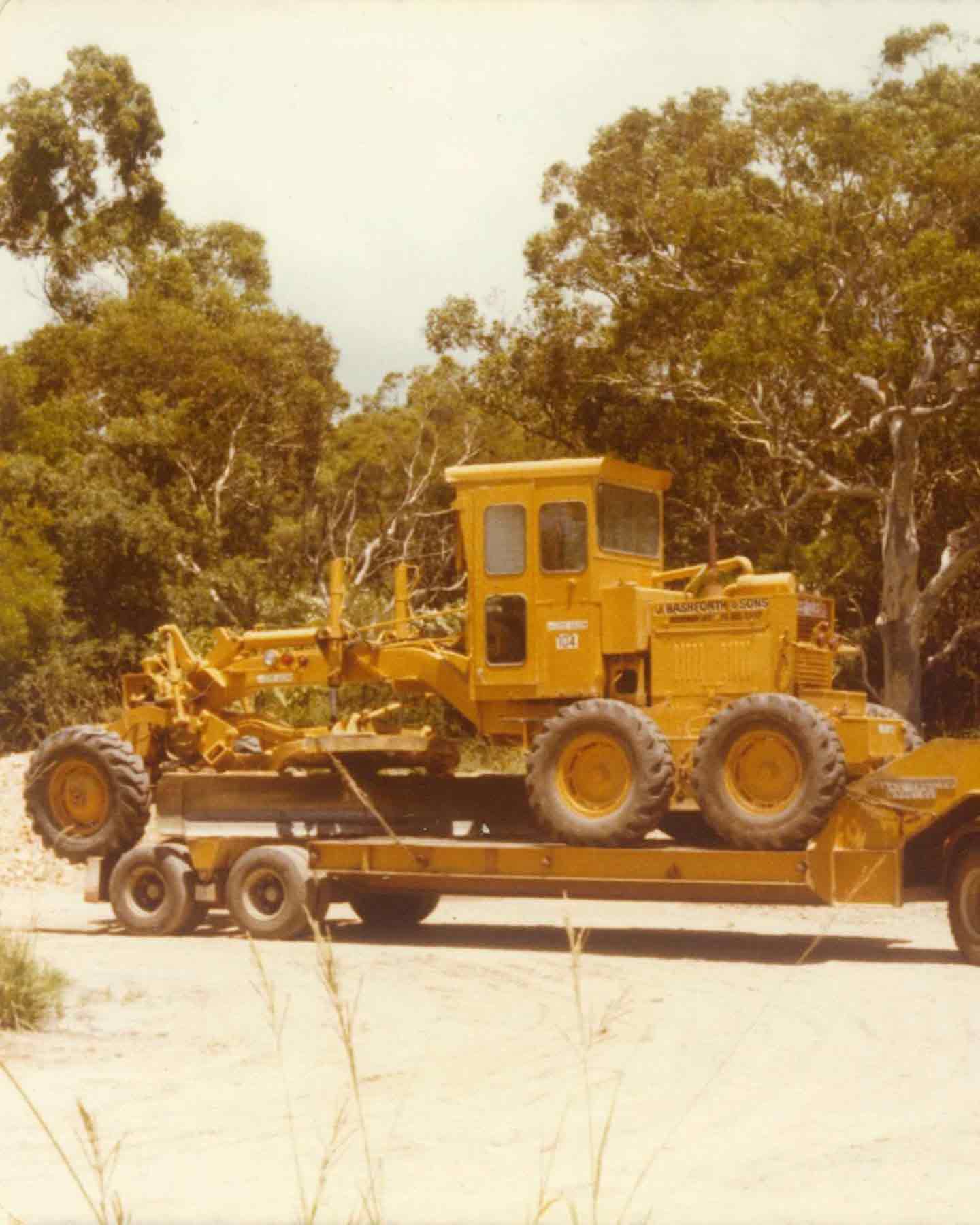 vintage-yellow-motor-grader-loaded-onto-a-low-loader-trailer